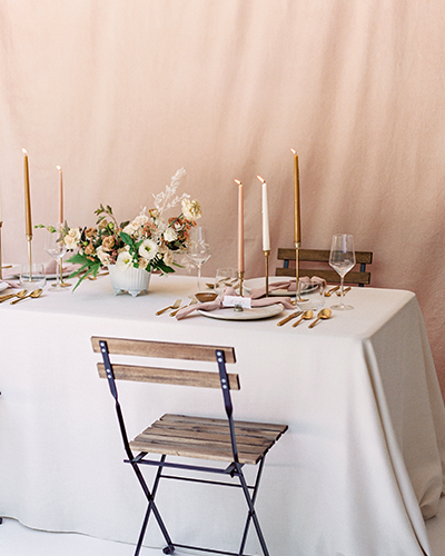 Blush wedding reception table with white linen and tapered candles